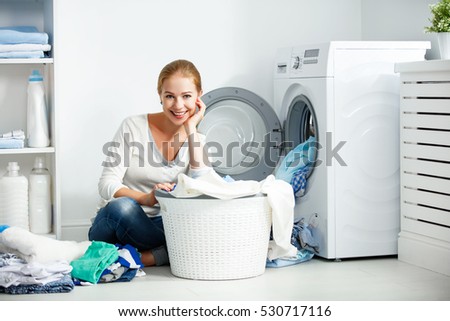 happy woman housewife in the laundry room near the washing machine with dirty clothes