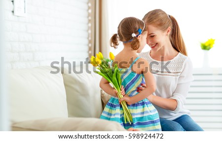 Happy mother's day! Child daughter congratulates moms and gives her a postcard and flowers tulips