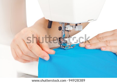 Hands of a seamstress at the sewing machine on a white background
