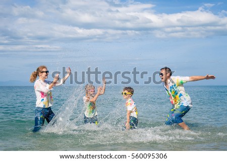 Happy family playing on the beach at the day time. People having fun outdoors. Concept of friendly family.