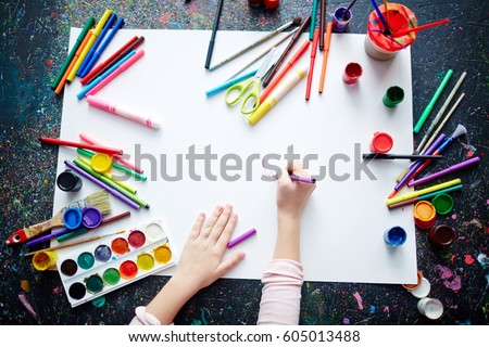 Hands of a kid drawing with highlighters on paper