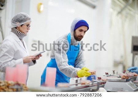 Control staff in uniform checking weight and quality of seafood during processing