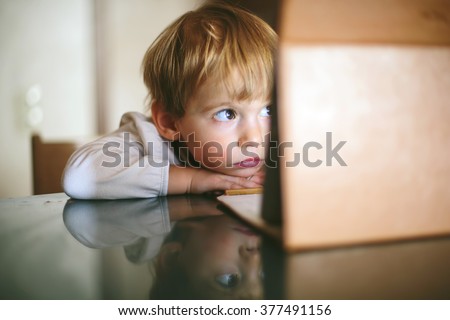 Little serious and lonely child Girl sitting and looking on tablet laptop