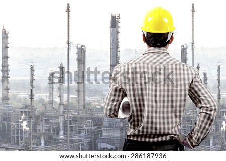 Technician holding blueprint for working at oil refinery petrochemical industrial plant