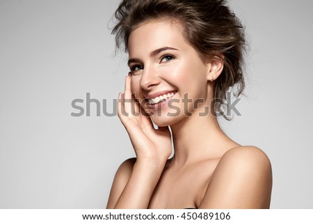 Beautiful smiling girl with clean skin, natural make-up, and white teeth on grey background