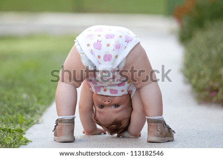 One-year baby girl playing upside down on the street