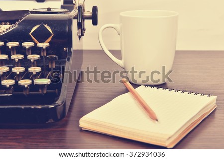 blank notebook, cup and vintage typewriter on the writer's desk