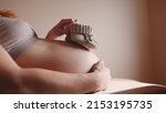 Small photo of happy pregnant woman. booties baby shoes on the belly of a pregnant woman. pregnancy health procreation concept. close-up belly of a pregnant woman. woman lifestyle waiting for a newborn baby