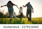 Small photo of happy family running in the park in summer. mom and dad hold their son by the hands run throw up in the forest park on the grass in the summer. happy family lifestyle kid dream concept
