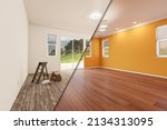 Small photo of Unfinished Raw and Newly Remodeled Room of House Before and After with Wood Floors, Moulding, Yellow Ochre Paint and Ceiling Lights.