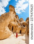 Small photo of Young beautiful woman in red dress exploring Pasabag Monks valley in Cappadocia Turkey with unique rock formations and fairy chimneys