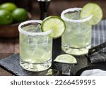 Margarita cocktail with ice, lime slice and salt rim on a black slate board