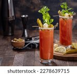 Small photo of Bloody mary cocktail garnished with celery, okra, onion, olive and salt rim on a ddark wooden background