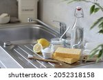 Vinegar and baking soda, lemon, natural sponge, toothbrush and towels on the kitchen sink. Natural and eco-friendly cleaning products.