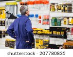 Rear view of worker with hands on hip standing in hardware store