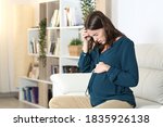 Pregnant woman suffering headache complaining sitting on a sofa in the living room at home