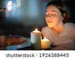 Relaxed woman smelling a lighted scented candle in the night at home