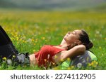 Side view portrait of a backpacker relaxing lying on the grass in nature