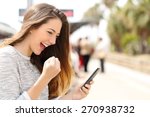 Euphoric woman watching her smart phone in a train station while is waiting 