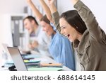 Three excited employees receiving good news on line in their laptops at office