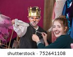 Small photo of Child actor dressed as king with crown brandishes sword as assistant helps him