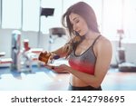 Small photo of A fit sportswoman standing in a gym and taking pre workout pills.