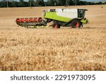 Small photo of combine harvester with unhooked header cutter, transports for harvesting work, on the background of stubble