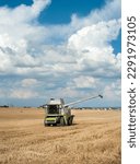 Small photo of Wheat fields and harvester with removed unhooked header cutter,the end of the grain harvesting process under a beautiful blue sky, cumulus clouds on a summer day.
