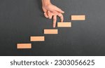 Small photo of Hand liken person stepping up a toy staircase wood