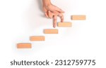 Small photo of Hand liken person stepping up a toy staircase wood