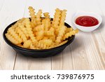 Close Up Shot Of Crinkle Cut French Fries In The Black Disposal Bowl And Ketchup Tomato Sauce On The Side  On The Light Color Wooden Table Fast Food Restaurant Concept