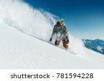 male snowboarder curved and brakes spraying loose deep snow on the freeride slope