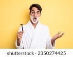 young handsome man feeling extremely shocked and surprised. shaving and foam concept