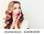 Shocked and surprised girl screaming and  looking to the side presenting  your product . Curly hair woman amazed .Beautiful girl  with curly hair and red nails manicure. Expressive facial expressions