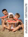 Small photo of happy father with children eating watermelon on the seabeach