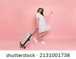 Small photo of Happy young Asian woman traveler drag luggage isolated on pink background, Tourist girl having cheerful holiday trip concept, Full body composition
