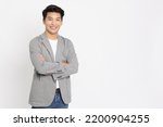 Small photo of Young Asian businessman smilling with arms crossed isolated on white background