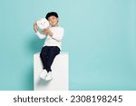 Small photo of Portrait of happy Asian little boy holding white piggy bank isolated on green background, Saving money and financial economize concept