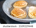 Frying kefir based pancakes in cooking pan on an electric stove.