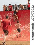 Small photo of CONYERS, GA - AUGUST 22: Competitors gather momentum as they run toward and climb up a wall obstacle at an amateur obstacle course race open to the public on August 22, 2015 in Conyers, GA.