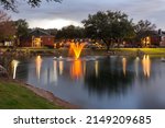 Small photo of Plano, Texas, USA - March 14th, 2022: Pond with illuminated at dusk fountains in the residential zone. The Steepleschase apartments complex