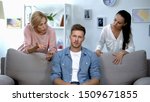Small photo of Irritated man sitting on sofa, listening wife and mother reproach, problem