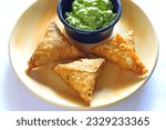 Small photo of Closeup of crispy,deep fried samosas which are hot favorite snacks in India served with fresh tangy mint chutney or dip or sauce.Samosas are invariably triangular can be vegetarian or non vegetarian
