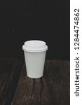 Small photo of White hot coffee cup placed on a wooden table with a black backg