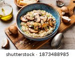 Risotto with brown champignon mushrooms on wooden background. 