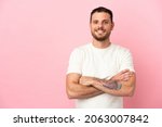 Small photo of Young Brazilian man isolated on pink background keeping the arms crossed in frontal position