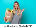 Small photo of Young Uruguayan woman holding a grocery shopping bag isolated on blue background intending to realizes the solution while lifting a finger up