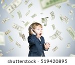 Cute toddler wearing a suit and talking on his smartphone is standing under a dollar rain in a gray room