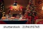 Small photo of Empty traditional Christmas dinner table inside decorated living room with holiday garlands and dinnerware. Interior of traditional and authentic season cozy setting celebrating religious event.