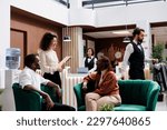 Small photo of Woman welcoming hotel guests in lobby, providing excellent luxury service to people at resort. Young manager discussing about staff and accommodation with tourists, giving advice.